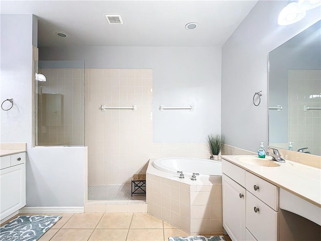 12854 Carrington Circle, Unit 204 Naples, FL 34105 - Photo 20 of 37 a bathroom with a double vanity sink a mirror and a bathtub