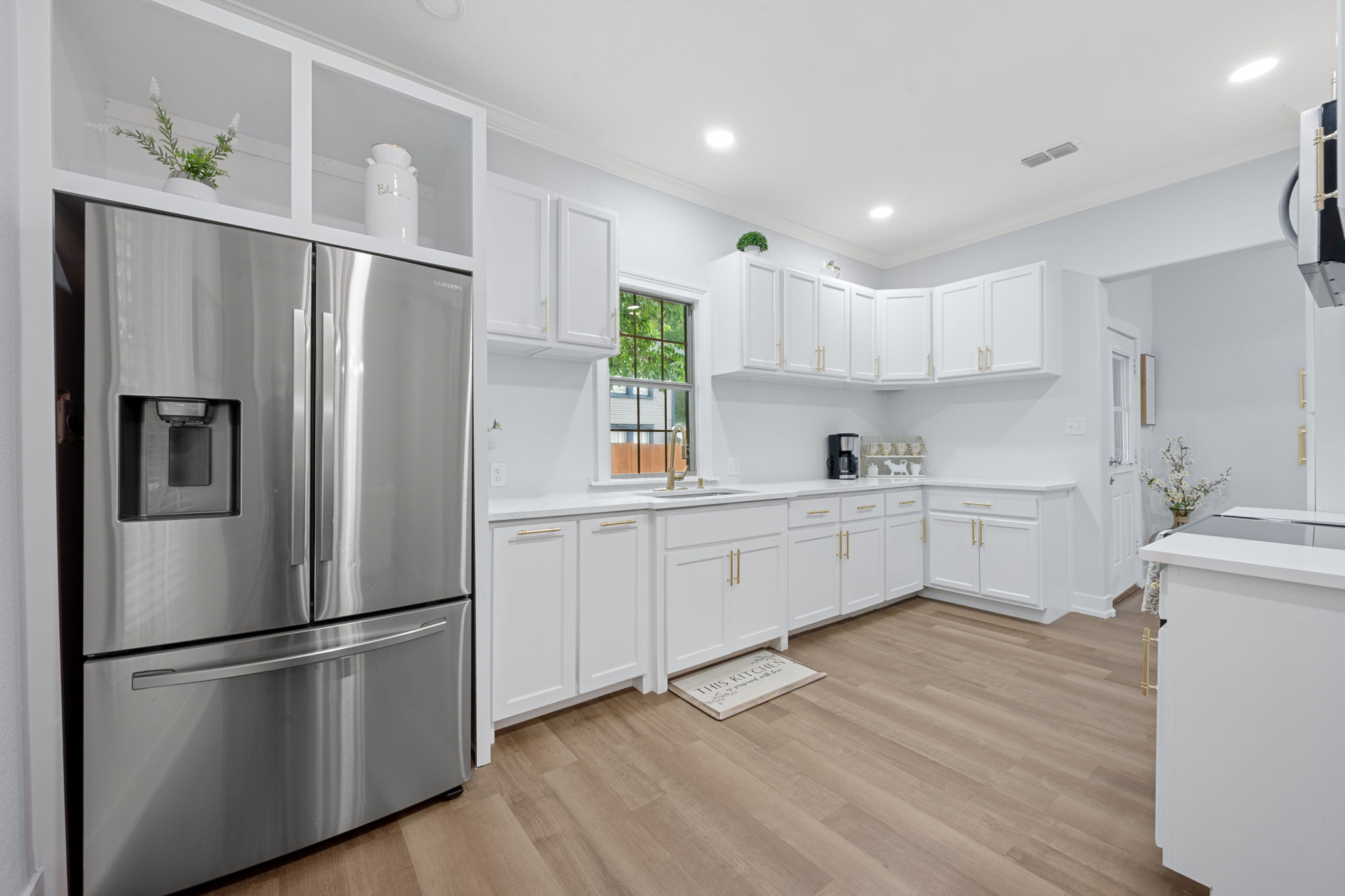 602 East 6th Street Cameron, TX 76520 - Photo 19 of 40 Contemporary kitchen featuring white cabinetry with gold-tone hardware, wood-finish flooring, recessed lighting, and a stainless steel French door refrigerator