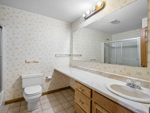 a bathroom with a granite countertop sink a toilet and a mirror