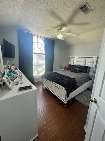 a bedroom with a bed and a flat tv screen on dresser