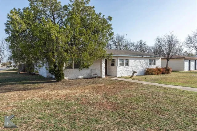 a front view of a house with a garden and tree