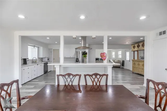 a kitchen with stainless steel appliances a dining table chairs and stove
