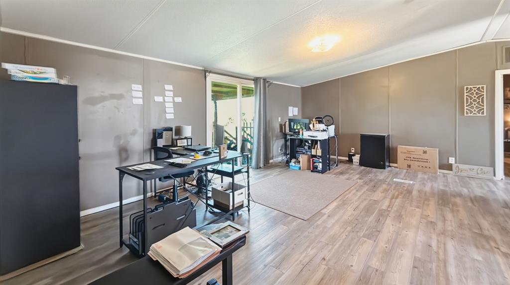 185 Private Road 4437 Rhome, TX 76078 - Photo 5 of 28 Spacious room featuring wood-finish flooring, neutral wall paneling, and a flush-mount ceiling light