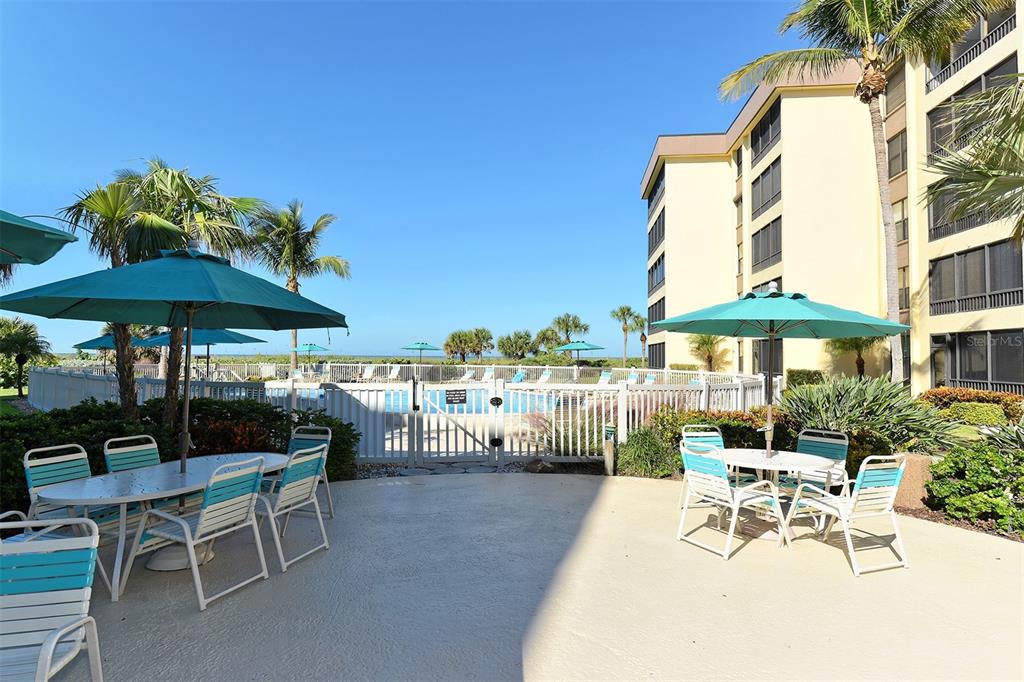 8764 Midnight Pass Road, Unit A306 Sarasota, FL 34242 - Photo 11 of 53 a view of a patio with a table and chairs under an umbrella