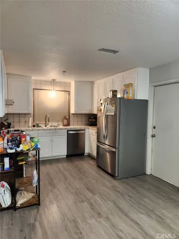 a kitchen with a refrigerator a microwave a sink and wooden floor