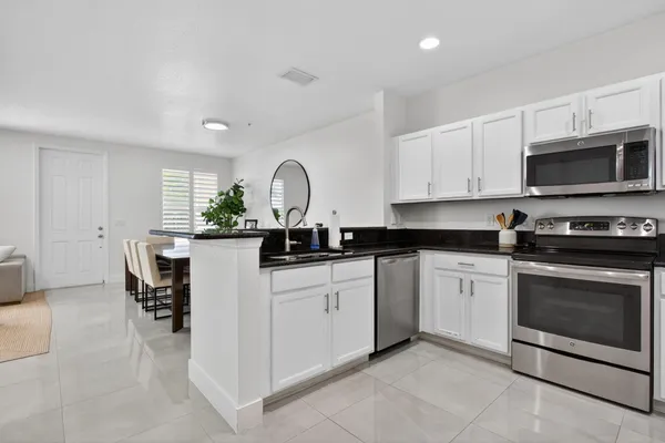 a kitchen with granite countertop white cabinets and stainless steel appliances