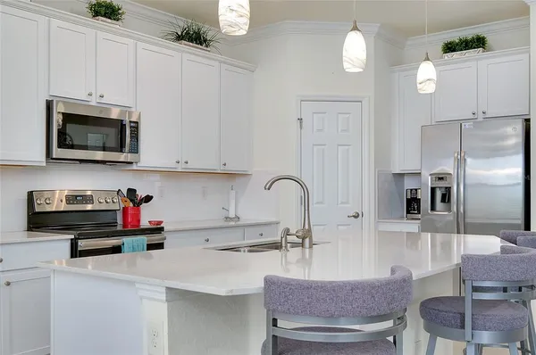a kitchen with stainless steel appliances a stove a sink a microwave and white cabinets