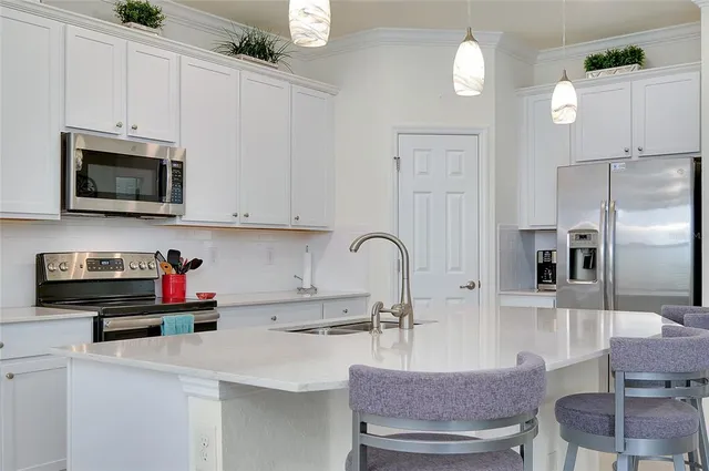 a kitchen with stainless steel appliances a stove a sink a microwave and white cabinets