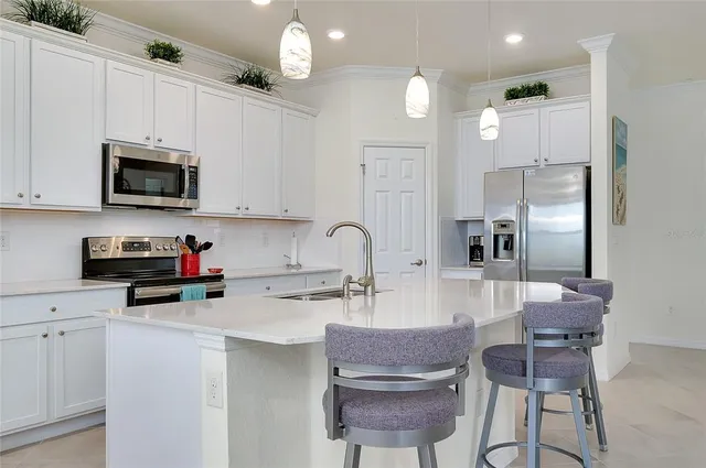 a kitchen with stainless steel appliances a table chairs refrigerator and microwave