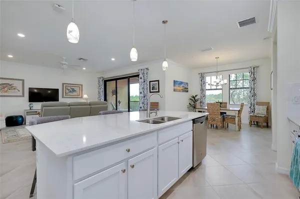 a kitchen with stainless steel appliances kitchen island a sink dishwasher a refrigerator and white cabinets with wooden floor