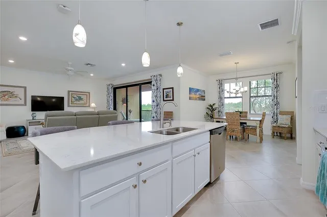 a kitchen with stainless steel appliances kitchen island a sink dishwasher a refrigerator and white cabinets with wooden floor