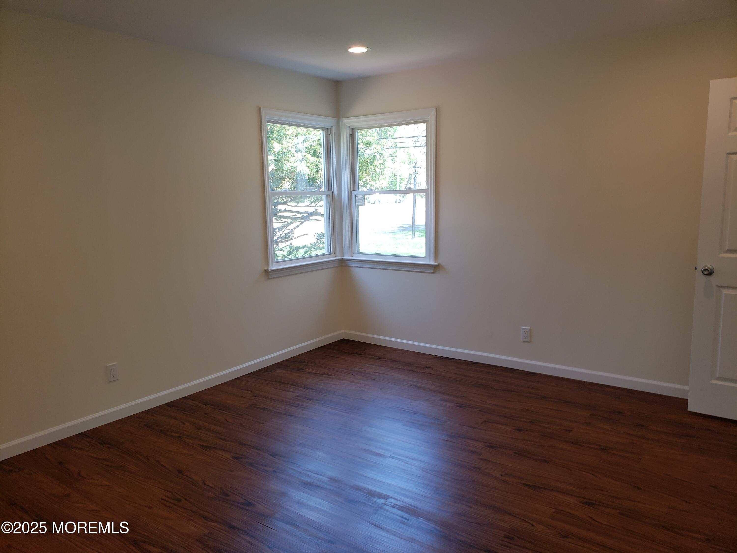 158 Monmouth Road Oakhurst, NJ 07755 - Photo 12 of 19 an empty room with wooden floor and windows