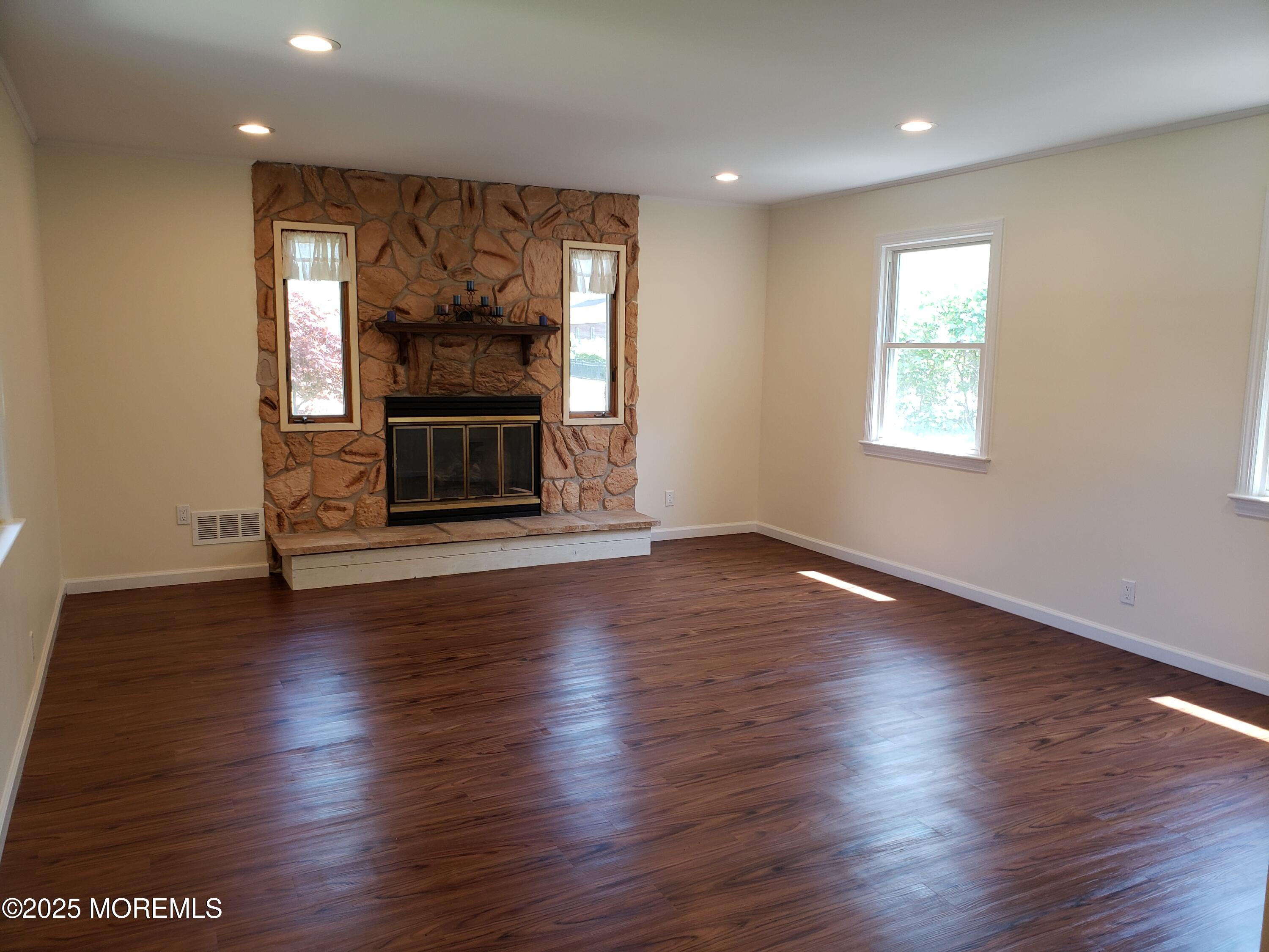 158 Monmouth Road Oakhurst, NJ 07755 - Photo 3 of 19 an empty room with wooden floor fire place and windows
