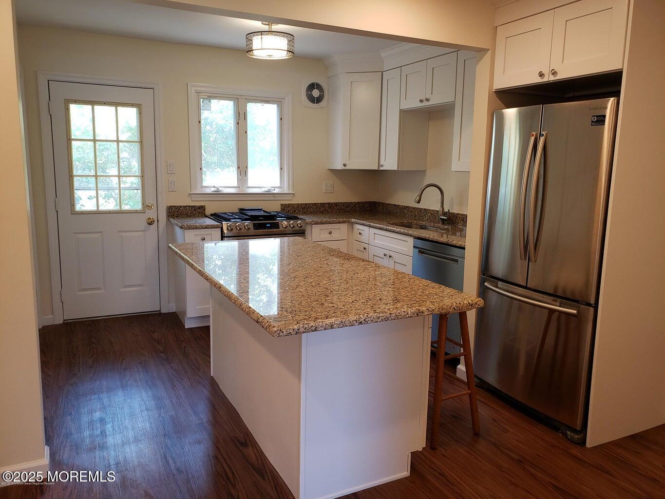 158 Monmouth Road Oakhurst, NJ 07755 - Photo 4 of 19 a kitchen with stainless steel appliances granite countertop a refrigerator a sink dishwasher a stove and white countertops with wooden floor