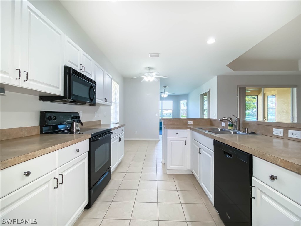 20599 Ardore Lane Estero, FL 33928 - Photo 16 of 29 a large kitchen with stainless steel appliances granite countertop a sink and dishwasher a stove top oven with white cabinets