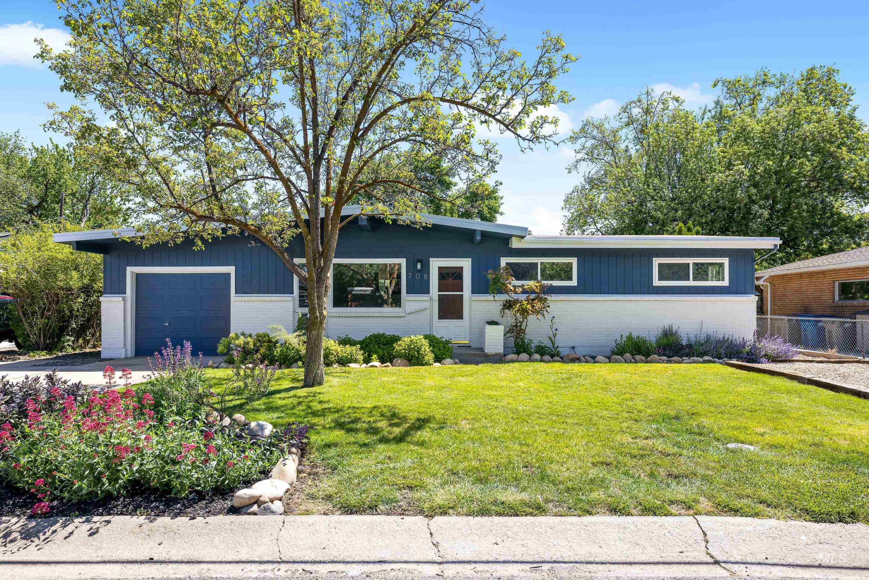 708 South Phillippi Street Boise, ID 83705 - Photo 1 of 25 Contemporary ranch-style exterior featuring a blue and white facade, an integrated garage, a manicured lawn, and mature landscaping