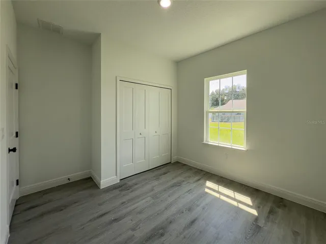 an empty room with a window and wooden floor