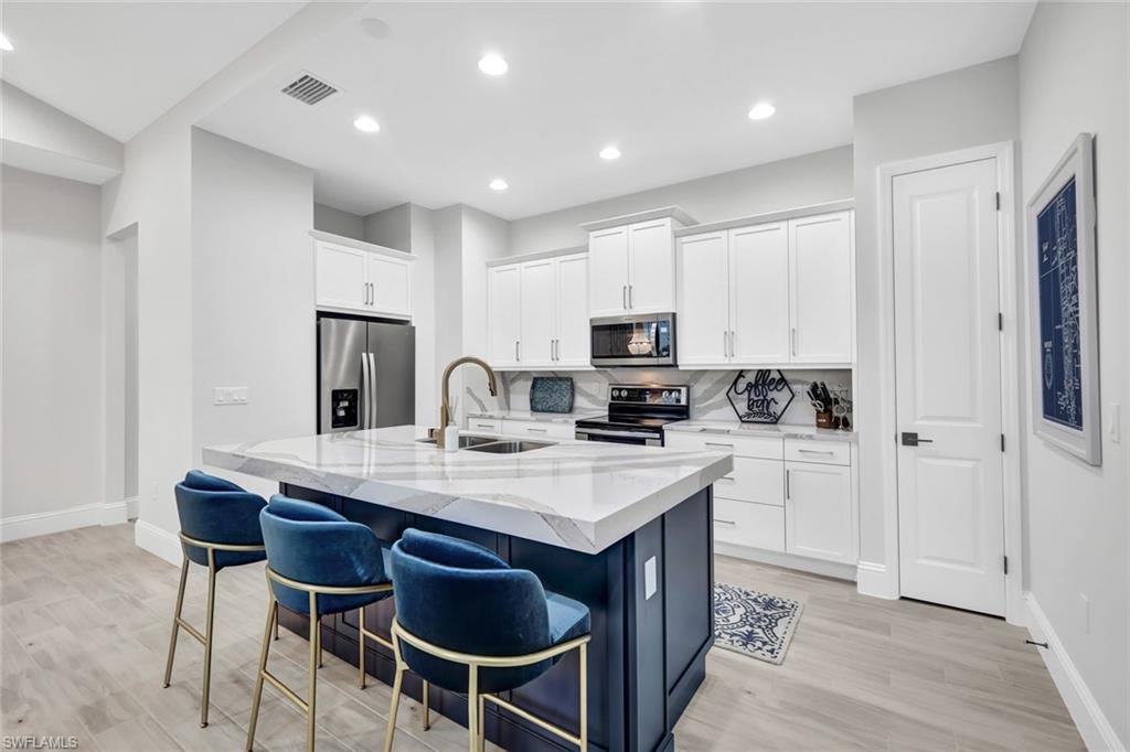 7142 Cayo Coco Lane Naples, FL 34113 - Photo 1 of 17 a kitchen with stainless steel appliances granite countertop a stove a refrigerator a sink dishwasher a dining table and chairs with wooden floors