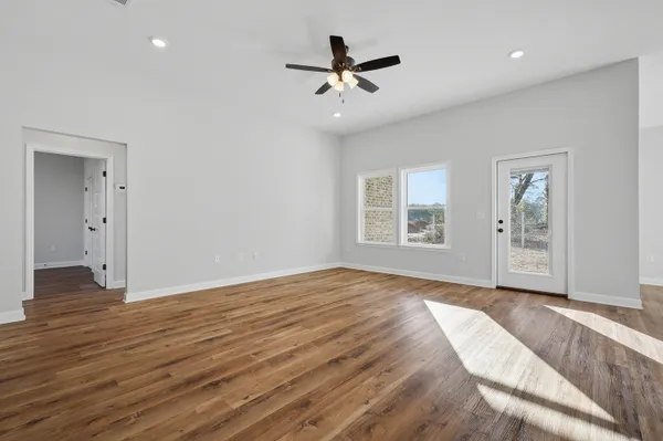 a view of an empty room with a window and wooden floor