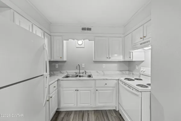 a kitchen with a sink dishwasher and white cabinets with wooden floor