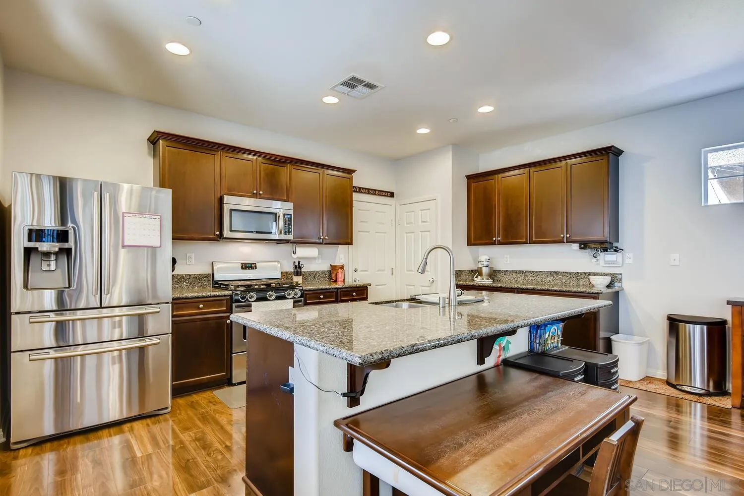 1223 Mason Road Chula Vista, CA 91913 - Photo 8 of 24 a kitchen with a refrigerator a stove top oven a sink dishwasher and wooden cabinets with wooden floor