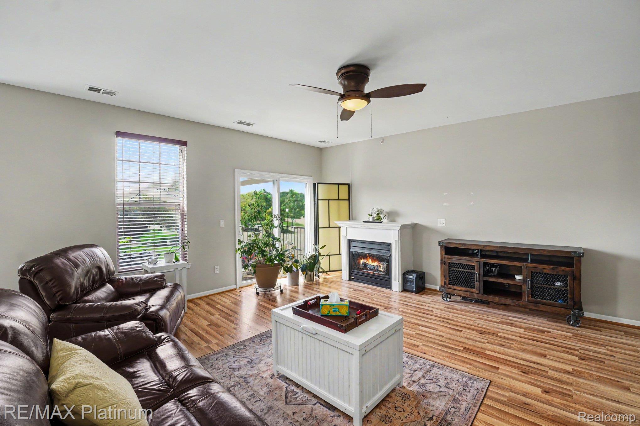 10217 Crossview Trail Howell, MI 48855 - Photo 6 of 26 Living space featuring wood-finish flooring, a white mantel fireplace, sliding glass door, and a ceiling fan