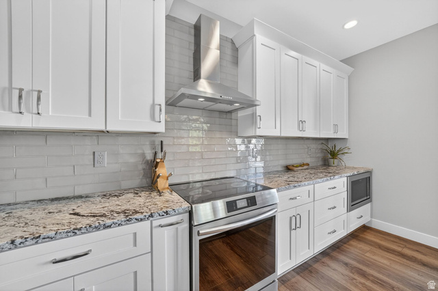 7872 Farm House Lane Midvale, UT 84047 - Photo 12 of 39 Modern kitchen featuring white shaker cabinetry, speckled countertops, a stainless steel range with a coordinating hood, a built-in microwave, and wood-finish flooring