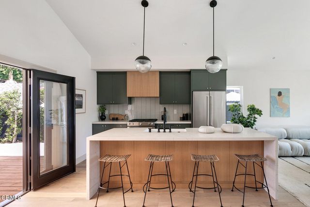 a kitchen with stainless steel appliances granite countertop a sink a stove a refrigerator and island with wooden floor