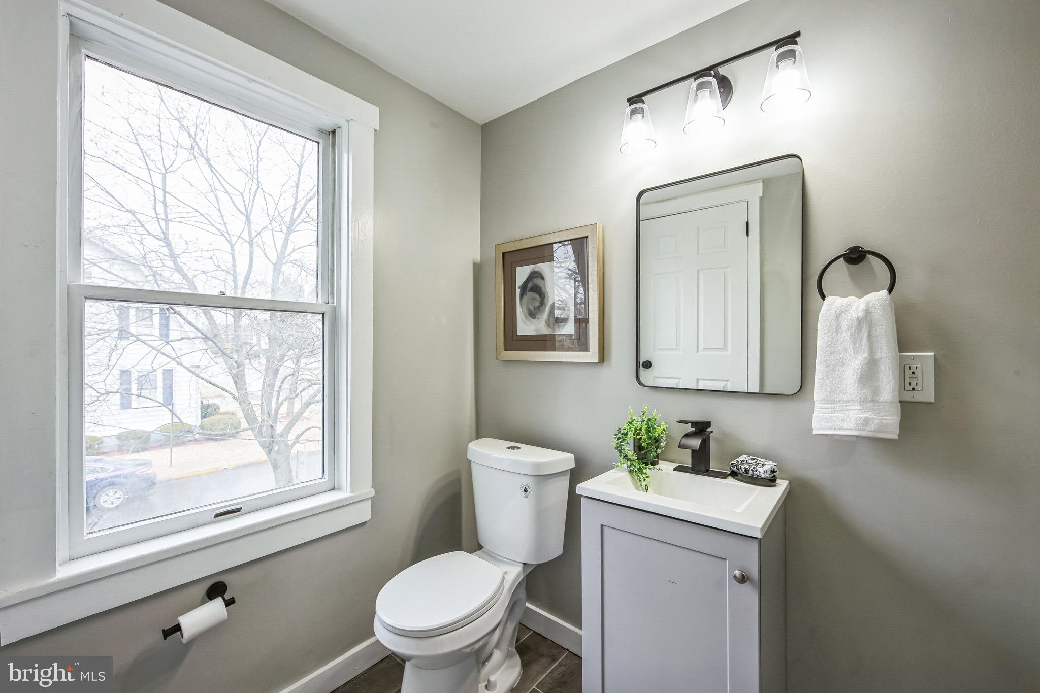 409 Neck Road Burlington, NJ 08016 - Photo 17 of 27 a bathroom with a toilet a sink a mirror a window and vanity