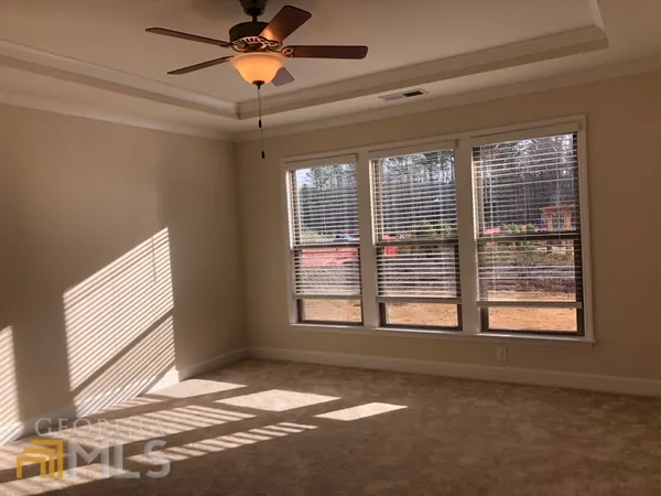 a view of an empty room with window and a kitchen