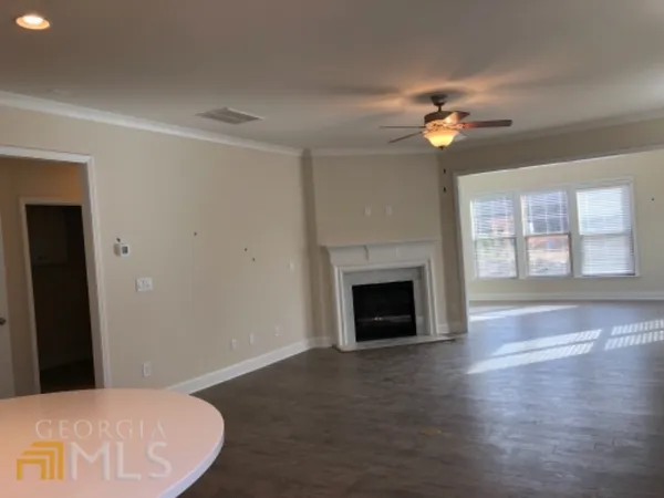 a view of a livingroom with a fireplace a ceiling fan and wooden floor