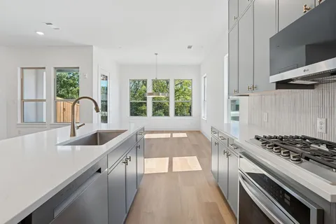 a kitchen with granite countertop a sink a stove and cabinets