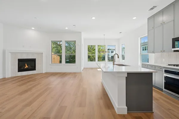 a large kitchen with stainless steel appliances a large counter top a stove and a wooden floors