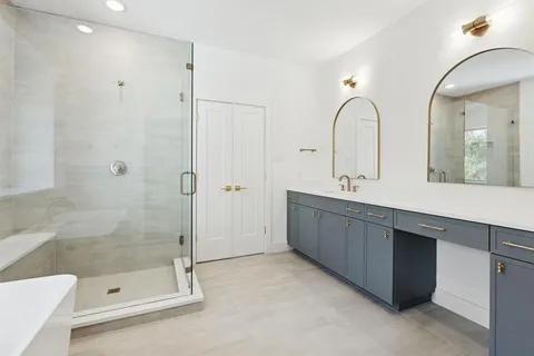 a bathroom with a tub shower a sink and a mirror