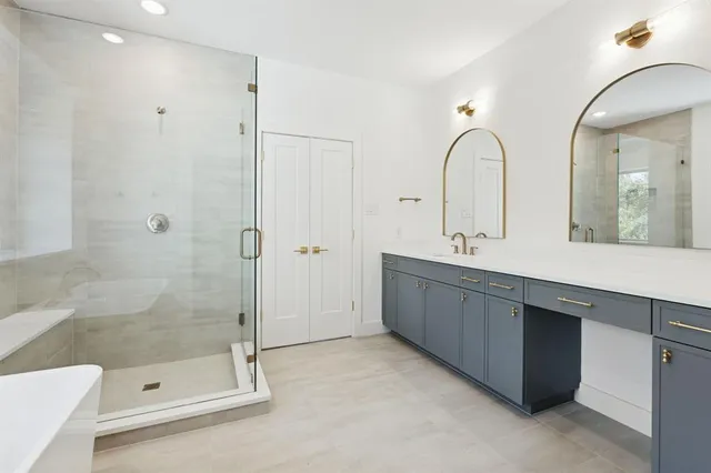 a bathroom with a tub shower a sink and a mirror