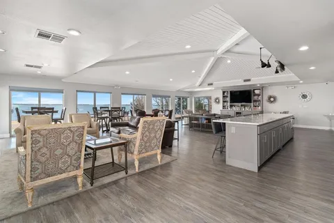 a living room with lots of white furniture and wooden floor