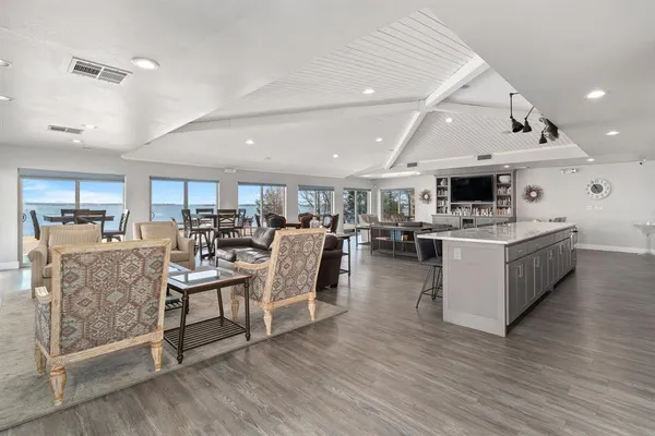 a living room with lots of white furniture and wooden floor
