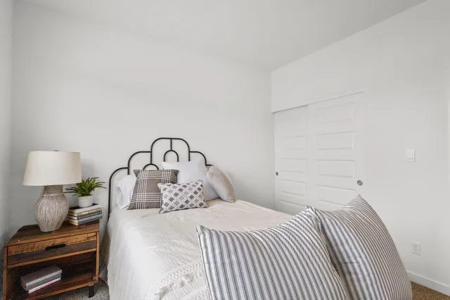 a bedroom with a bed and a lamp on dresser