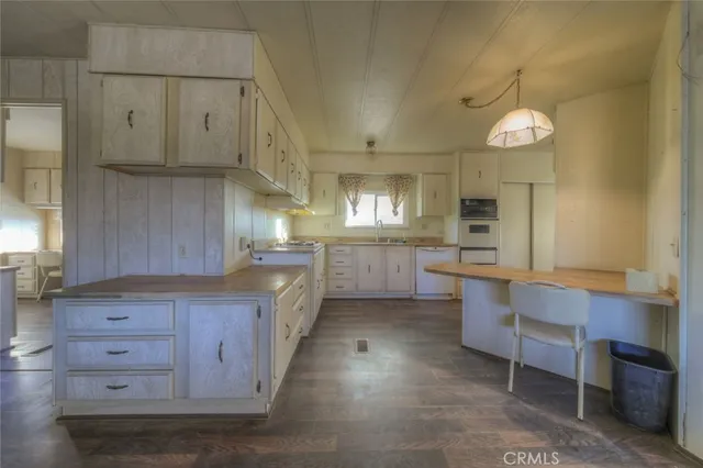 a large kitchen with granite countertop a stove a sink dishwasher a dining table and chairs with wooden floor