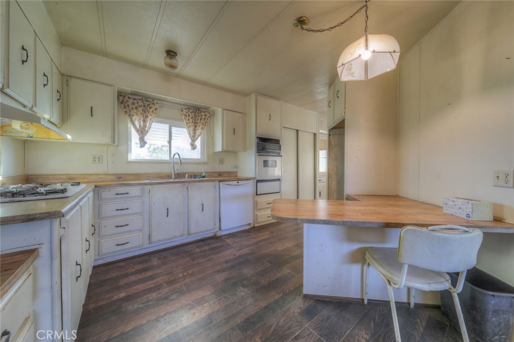 52565 Wheeler Road Anza, CA 92539 - Photo 12 of 54 a large kitchen with granite countertop a stove a sink dishwasher a dining table and chairs with wooden floor