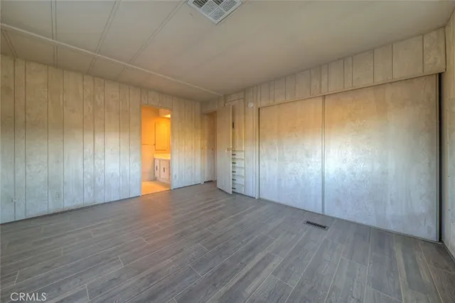 an empty room with wooden floor closet and windows
