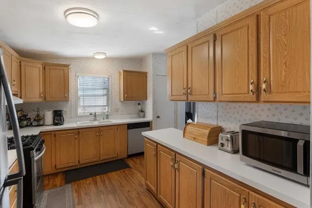 a kitchen with stainless steel appliances granite countertop wooden cabinets a sink and dishwasher a stove with wooden floor