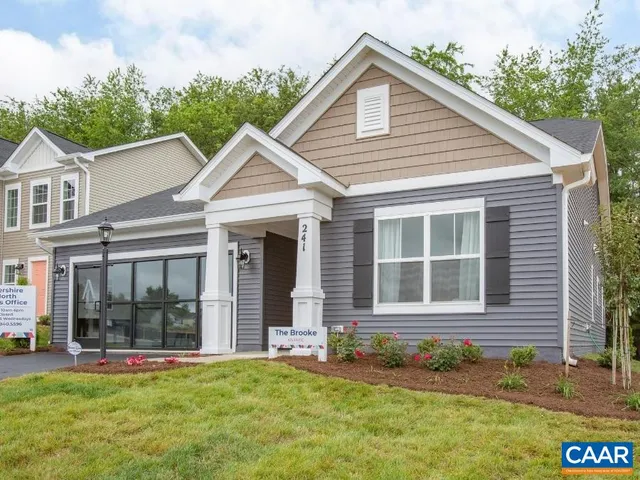 a view of a white house with large windows and a yard with lawn chairs