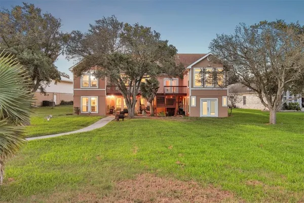 a view of a big house with a big yard and large trees