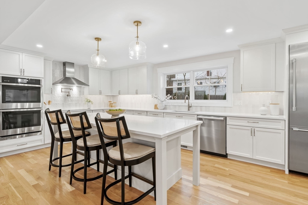 56 Valentine Road Arlington, MA 02476 - Photo 20 of 42 a kitchen with stainless steel appliances kitchen island granite countertop a table chairs sink and cabinets