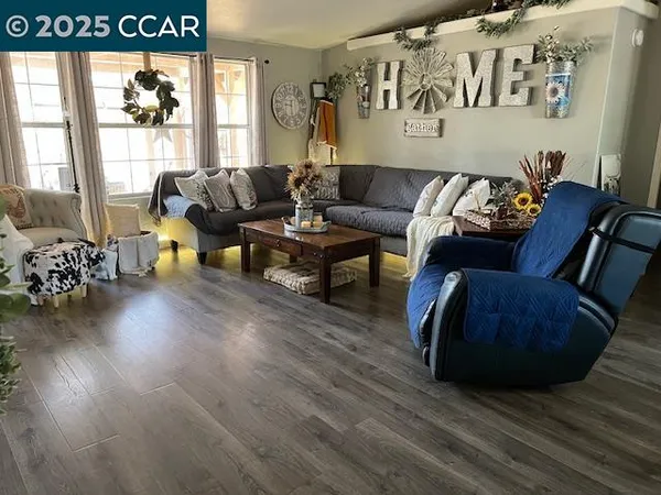 a room with stainless steel appliances kitchen island granite countertop a table chairs and a wooden floor