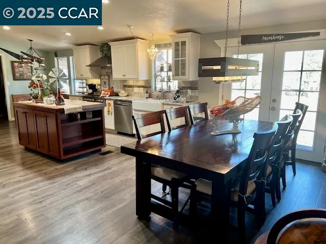 a kitchen with stainless steel appliances kitchen island granite countertop a refrigerator oven a sink dishwasher and white cabinets with wooden floor