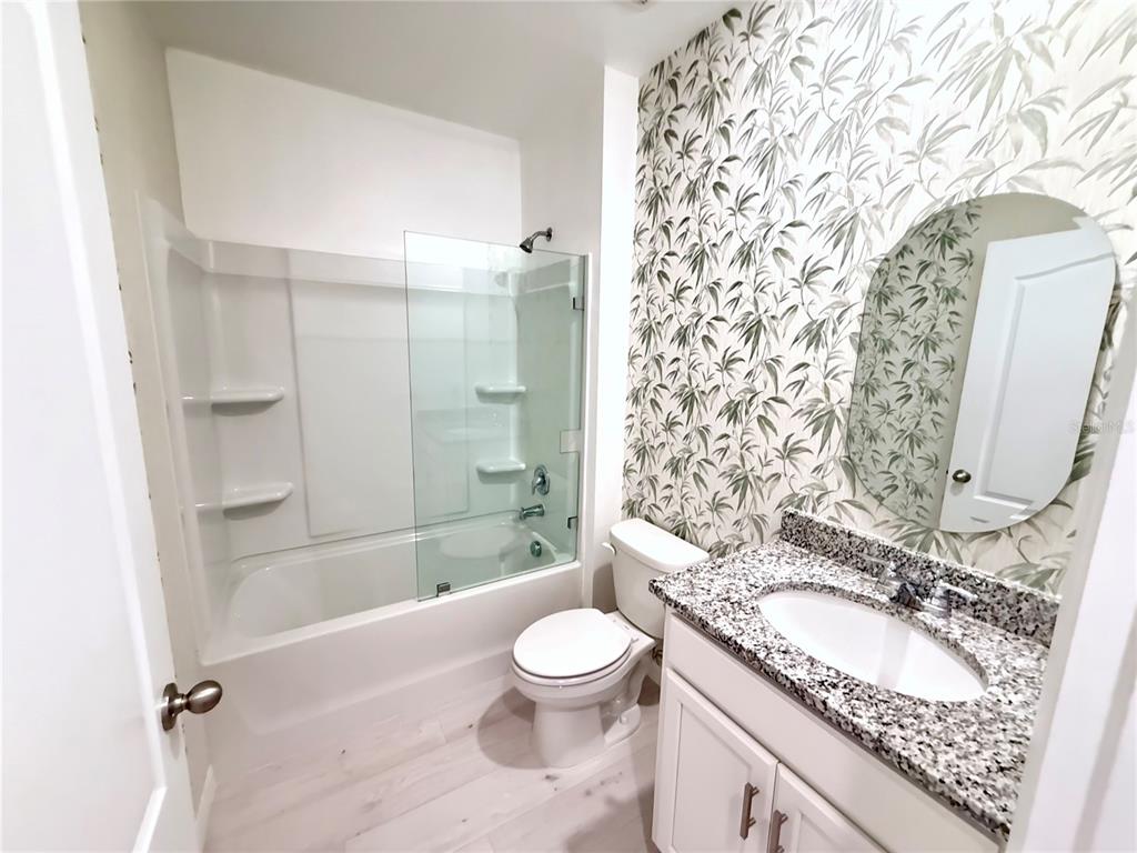 2731 House Finch Road Harmony, FL 34773 - Photo 22 of 57 a bathroom with a granite countertop sink toilet a shower and a mirror