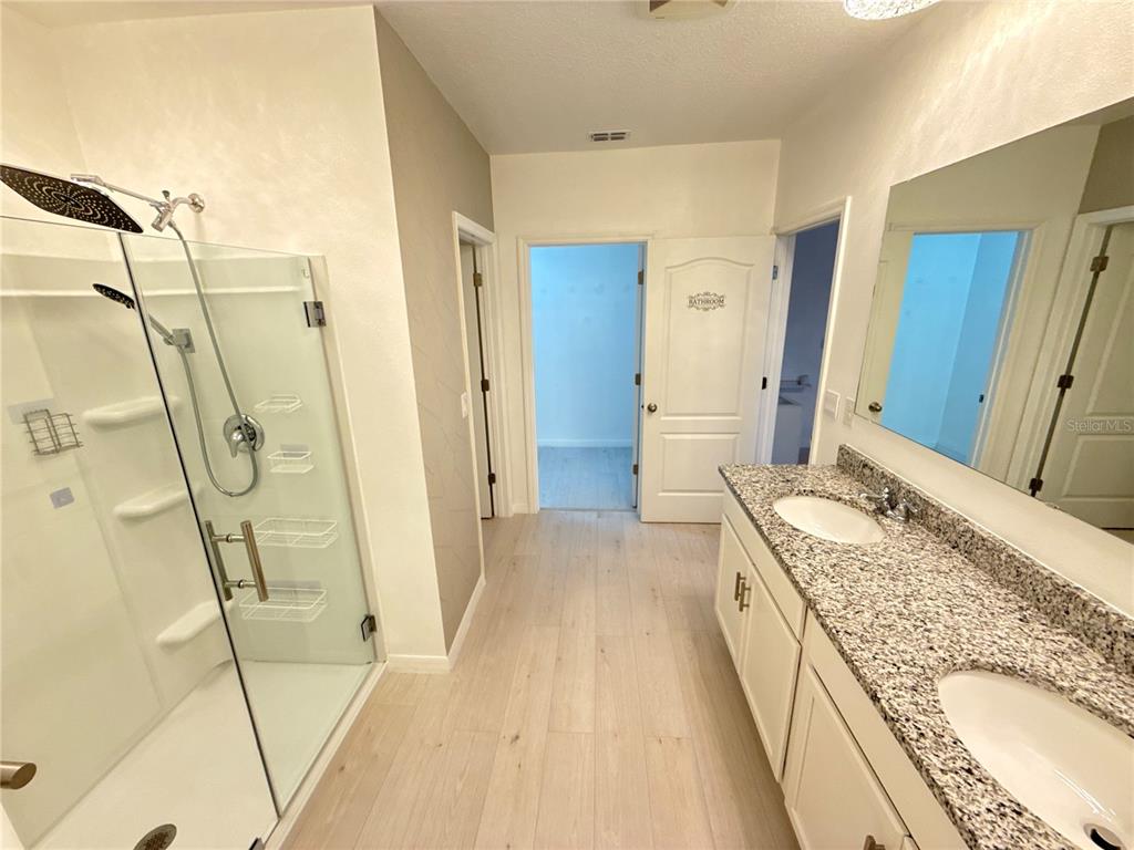 2731 House Finch Road Harmony, FL 34773 - Photo 37 of 57 a spacious bathroom with a granite countertop sink a mirror and shower