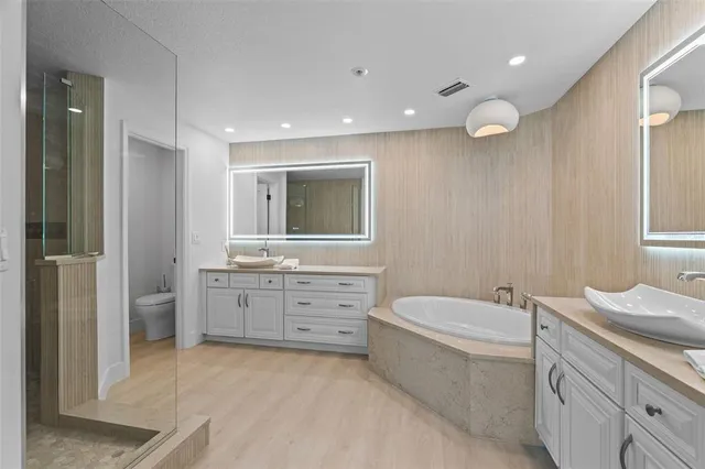 a bathroom with a granite countertop sink a toilet a mirror and shower